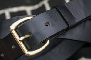 Macro shot of black leather belt and brass buckle