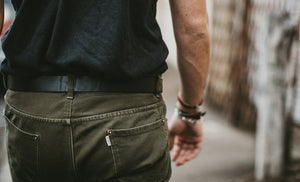 Backside closeup of adult male wearing green pants and black leather belt