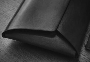 edge detail of green leather folding card wallet with brass stud closure