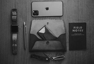 leather folding card wallet next to keychain and watch and phone