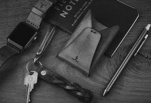 leather folding card wallet next to keychain and watch