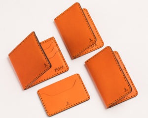 arrary of orange wallets ranging from minimal slim wallet to bifold style wallet