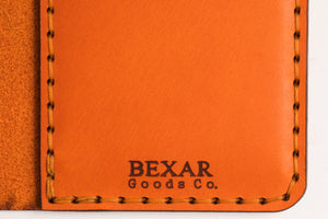 closeup of engraving on four pocket vertical orange leather wallet 