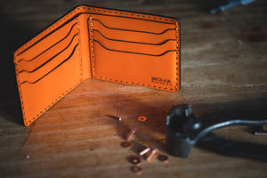 interior of Orange six pocket bifold wallet next to copper rivets