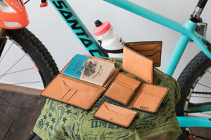 array of russet brown colored wallet next to bicycle