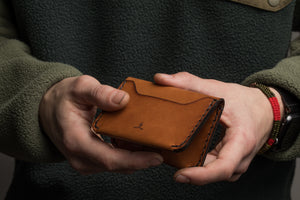 man holding three card brown leather wallet