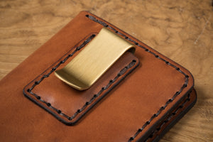 detail of brass money clip on brown leather four pocket vertical wallet 