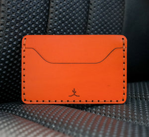 two pocket slim orange leather wallet on leather car seat