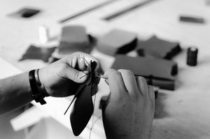 black and white of man handstitching leather wallets