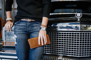 woman holding brown leather long wallet with eight card pockets and two cash sleeves in front of classic car