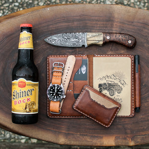 array of leather wallets next to drink, watch, and knife